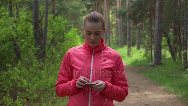 Ung vacker kvinna kör i höst park och lyssna på musik med hörlurar. — Stockvideo