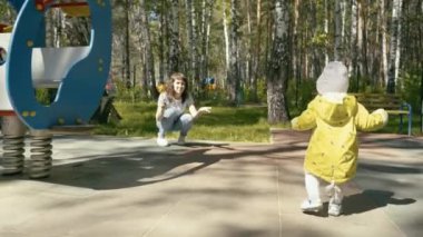 Küçük çocuk annesine gidiyor ve onu kucakladı. Parkta.