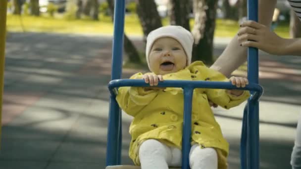 Mother pushing child on a swing set — Stock Video