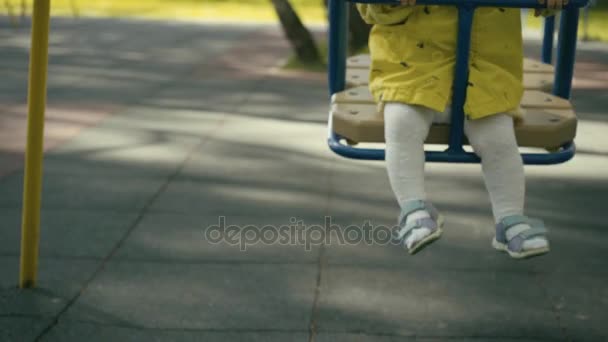 Mother pushing child on a swing set — Stock Video