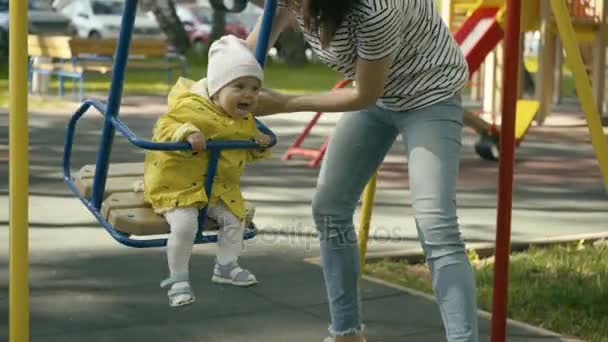 Madre spingendo bambino su un set altalena — Video Stock