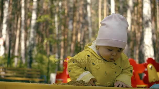 Bambina seduta nella sabbiera e che gioca con gli stampi nel parco giochi, i bambini che fanno forme all'aperto — Video Stock