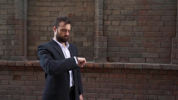 Man in a black business suit near a brick wall. — Stock Video