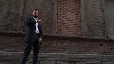 Dikkati işadamı cep telefonunu cebinden bir tuğla duvar kopya alanı ile birlikte kentsel bir kaldırım boyunca yürür çekerek