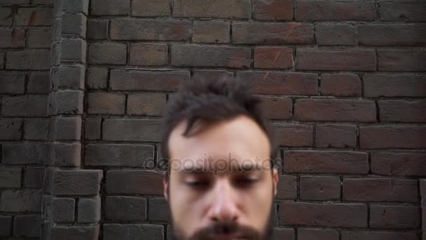 Estrés y problemas. Retrato de un joven angustiado, se encuentra en una casa abandonada sobre un fondo de una vieja pared de ladrillo — Vídeo de stock