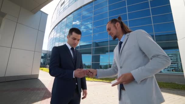 Двое бизнесменов обмениваются визитками и разговаривают — стоковое видео