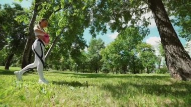 genç kadın yogini bir yoga mat Park yeşil çimenlerin üzerinde inişli çıkışlı