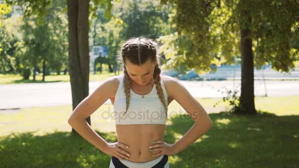 Dışarıda spor yapan bir kadın var. Dişi koşucu, yeşil ormanda maraton koşmadan önce geriniyor. Spor elbiseli sıska kız parkta esneme egzersizleri yapıyor. Açık hava egzersizi. — Stok video