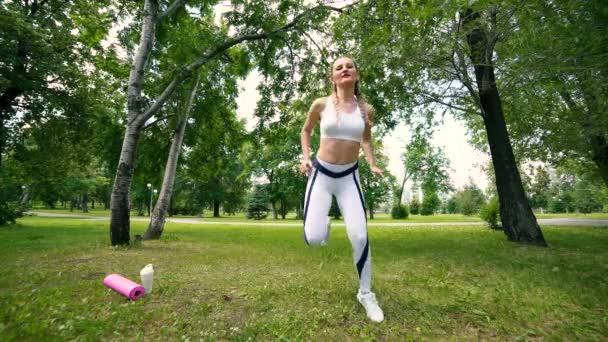 Sport junge Frau trainiert, treibt Sport im Park. Fitnessmädchen beim Ausfallschritt im Park im Sommer. Training an sonnigem Tag. — Stockvideo