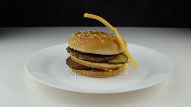 Fried potato chips falling down on hamburger, slow motion, fast food, junk food concept. — Stock Video