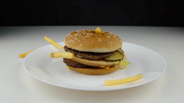 Croustilles frites tombant sur hamburger, ralenti, restauration rapide, concept de malbouffe . — Video