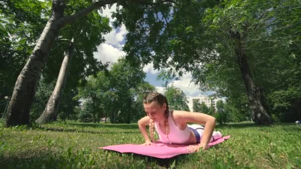 Flicka mediterar. Professionell yoga praktiserande i park gör andningsövningar. Ung brunett kvinna praktiserar yoga drag på grönt gräs på offentlig plats — Stockvideo