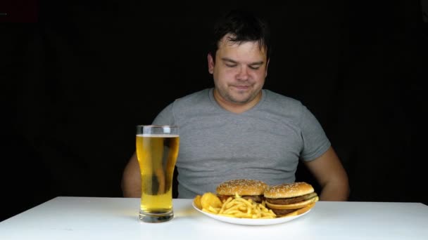 Diéta nem kövér ember evés gyorsétterem hamberger. Boldog mosollyal túlsúlyos, aki elrontotta egészséges élelmiszer eszik hatalmas hamburger a villát. Junk étkezés elhízás vezet. A káros ételek megtagadása. — Stock videók