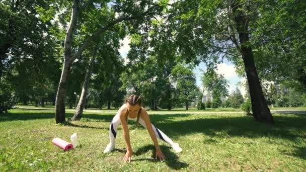 Mujer haciendo ejercicios de fitness al aire libre. Corredor hembra estirándose antes de correr maratón en bosque verde. Chica delgada en ropa deportiva haciendo ejercicios de estiramiento en el parque. Entrenamiento al aire libre — Vídeos de Stock