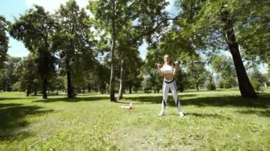 Genç kadın ile parkta niteliğine dışında ağır çelik dumbbell egzersiz spor. Fitness Egzersiz kızlar için açık havada.