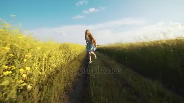 Una chica con el pelo largo corriendo por el camino en un día soleado de verano, vacaciones . — Vídeo de stock