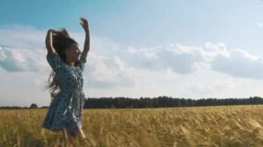 Güzellik esmer kız sağlıklı uzun saçlı iplik ve altın buğday sahada açık gülüyor. Doğanın keyfini. Genç kadın elbiseli açık eğleniyor. Günbatımı.