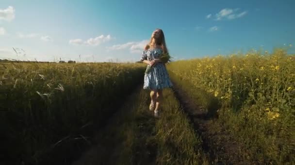Женщина держит кучу колосьев пшеницы и полевые цветы на поле — стоковое видео