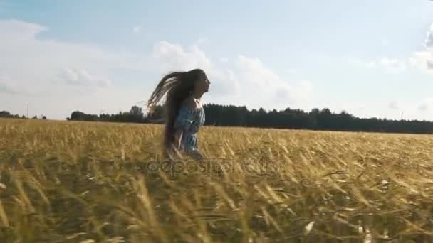 Красивая девушка бегает по залитым солнцем пшеничному полю. Медленное движение 120 кадров в секунду. Вспышка солнечных линз. Понятие свободы. Счастливая женщина веселится на свежем воздухе на пшеничном поле на закате или на восходе солнца. Медленное движение. Урожай . — стоковое видео