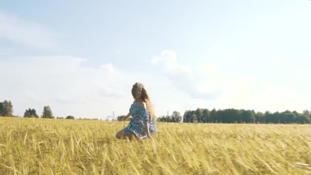 Menina bonita correndo no campo de trigo iluminado pelo sol. Movimento lento 120 fps. Inflação da lente solar. Conceito de liberdade. Mulher feliz se divertindo ao ar livre em um campo de trigo no pôr do sol ou nascer do sol. Movimento lento. Colheita . — Vídeo de Stock