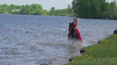 Güzel sarışın bir genç seksi kadın Kırmızı elbiseli bir gölde bir binicilik.