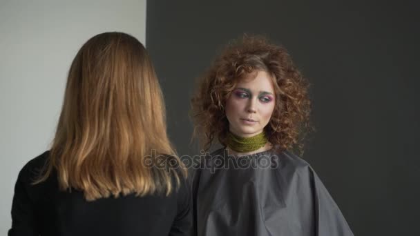 Vista de perto para o artista de maquiagem profissional está aplicando brilho de lábio vermelho a um modelo . — Vídeo de Stock