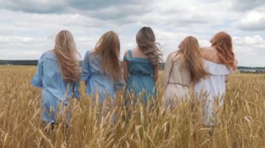 Altın buğday dolu bir alanda uzun sarı saçlı beş kız.