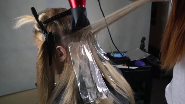 Парикмахер раскрашивает волосы в студии — стоковое видео