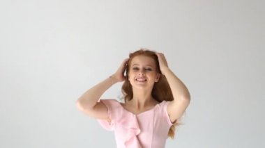 Uçan kıvırcık saçlı beyaz arka plan üzerinde kameraya bakarak gülen gülümseyen güzel neşeli Kızıl saçlı kız portresi.