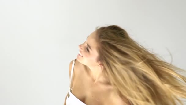Привлекательный улыбающийся женский портрет с длинным блондинистым слухом, смотрящий в камеру на белом фоне — стоковое видео