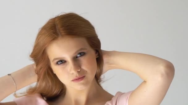 Retrato de hermosa chica pelirroja alegre con el pelo rizado volando sonriendo mirando a la cámara sobre fondo blanco . — Vídeos de Stock