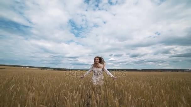 Tam uzunlukta kaçarken buğday alanda beyaz elbiseli güzel bir genç mutlu kadın portresi — Stok video