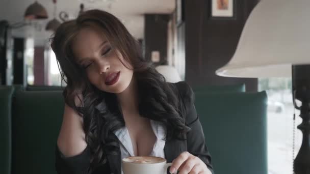 Krásná mladá žena se těší cappuccino káva s pěnou u okna v kavárně