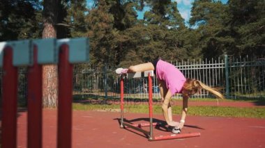 Bir kadın atlet bir engel atlar. Çalıştırmadan önce ısınmak