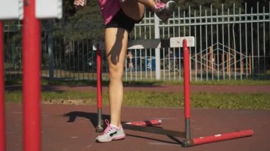 Bir kadın atlet bir engel atlar. Çalıştırmadan önce ısınmak