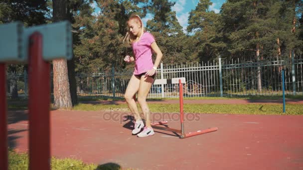 Une coureuse saute par-dessus un obstacle. Réchauffer avant de courir — Video