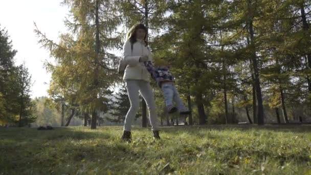 Grandes jovens mães na moda andando no parque com suas filhas em roupas bonitas — Vídeo de Stock