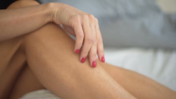 Sexy mujer de cabello castaño en ropa interior erótica se encuentra en la cama y toca su cabello con su mano . — Vídeo de stock