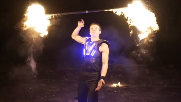Пожарное шоу. Красавчик-пожарный жонглер, манипулирующий огненной дубинкой несколькими фитилями — стоковое видео