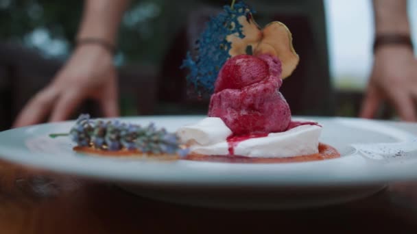 Σε ένα καθαρό άσπρο τραπέζι είναι ένα πιάτο με ένα μεγάλο παγωτό που ορίζονται. Μορφή παγωτού σε μορφή πουρέ. Ροζ χρώμα. Περιστρέψτε την πλάκα. Κρύο επιδόρπιο. Παγωτό φρούτα. — Αρχείο Βίντεο