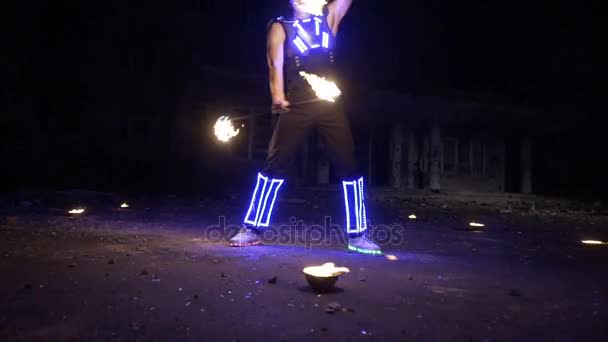 Fire show performance. Handsome male fire performer twirling and tossing up fire baton staff ignited from both sides. — Stock Video