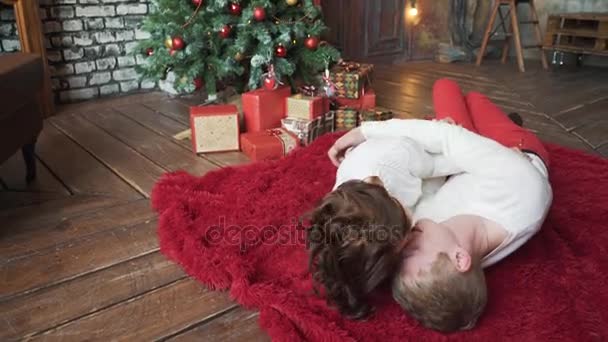 男孩和女孩亲吻在圣诞树附近。真正的爱和感情特写的一个迷人的, 可爱的, 感性的可爱的朋友拥抱, 黑发的女士与灿烂的笑容. — 图库视频影像