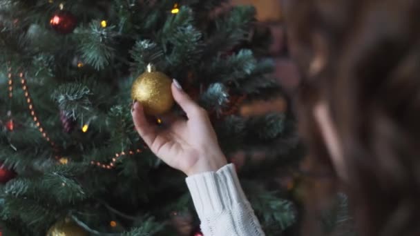 Joven hermosa chica decora el árbol de Navidad, mientras que su novio tiene un regalo de Navidad . — Vídeos de Stock
