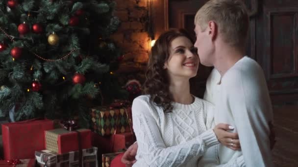 Happy young people give each other gifts by the fireplace near the Christmas tree. — Stock Video