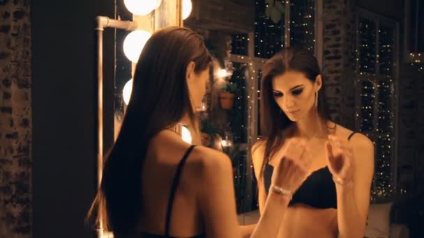 Portret van een mooie vrouw proberen op zwarte ondergoed voor een spiegel. — Stockvideo