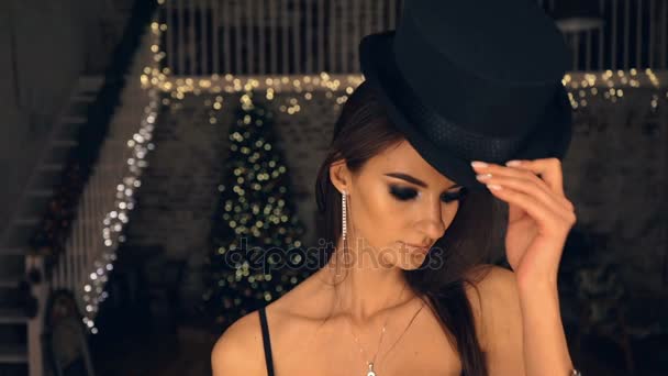 Schönes Mädchen, das am Spiegel steht und einen Hut anprobiert. die Frau in schwarzer Unterwäsche. — Stockvideo