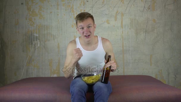 Mladý muž, pití piva na doma gauč a sledování televize — Stock video