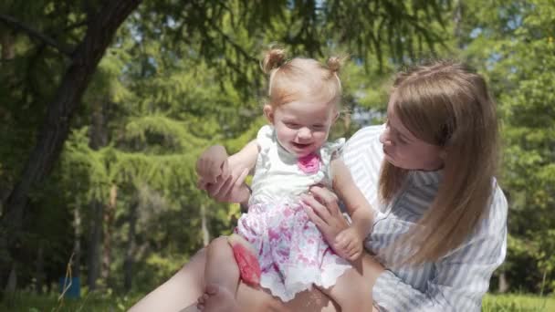 The family of two people, mother and young daughter spending time together in the city Park for a picnic. Young woman and little girl eating fruit. — Stock Video