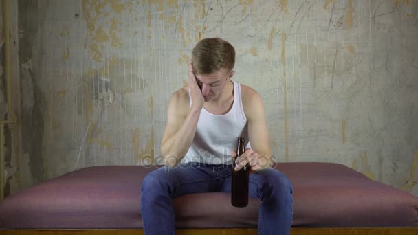 Пьяный молодой человек пьет пиво дома . — стоковое видео