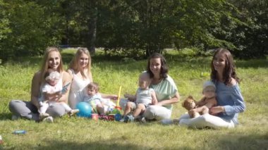 Mutlu çocuklar açık havada yaz parkta oyun grubu. Anneler çocuklarını çimlere oturup sonra bak.